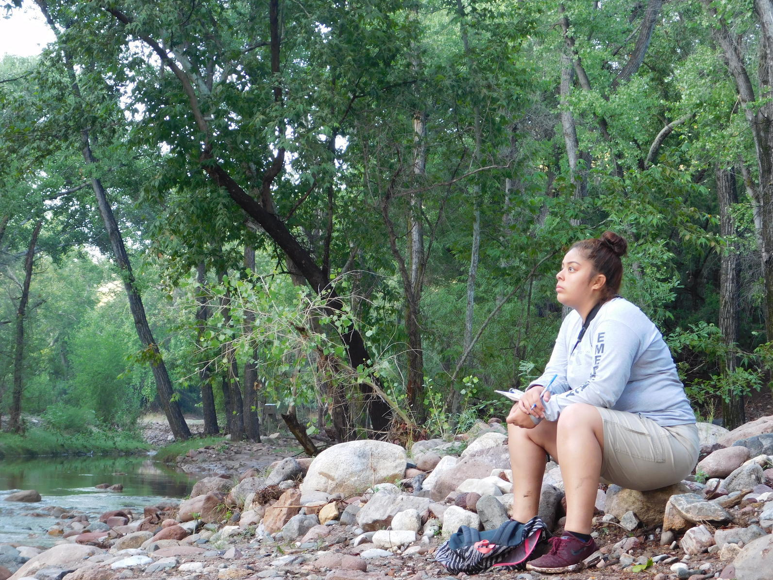 Aritzel Baez, one of last year's summer interns, looks at foliage along the riverbank.