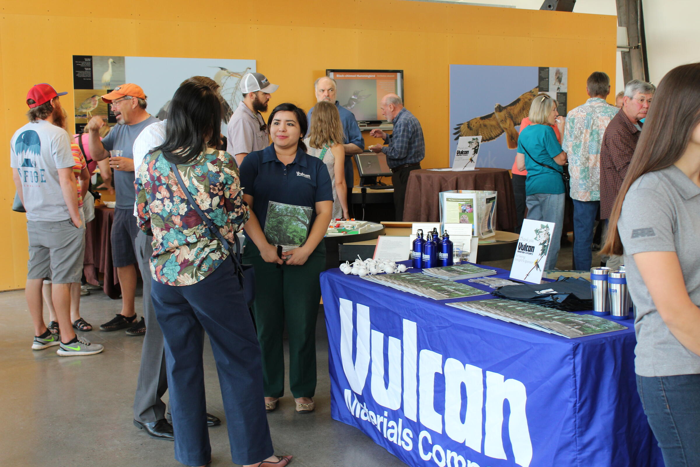 People mingle around the center and interact with a sponsorship booth from Vulcan Materials company during Birds n' Beer.