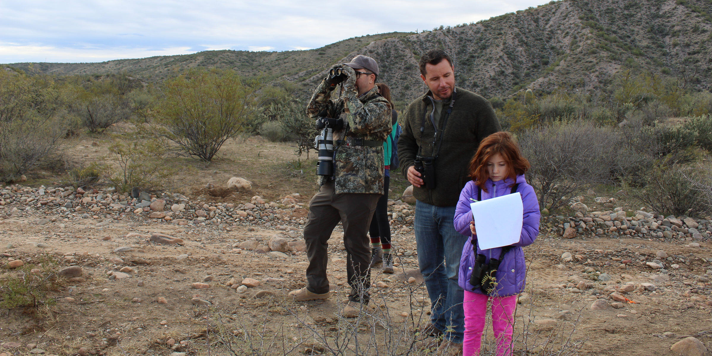 A group of adults and a child conduct a bird count in a cold desert environment.