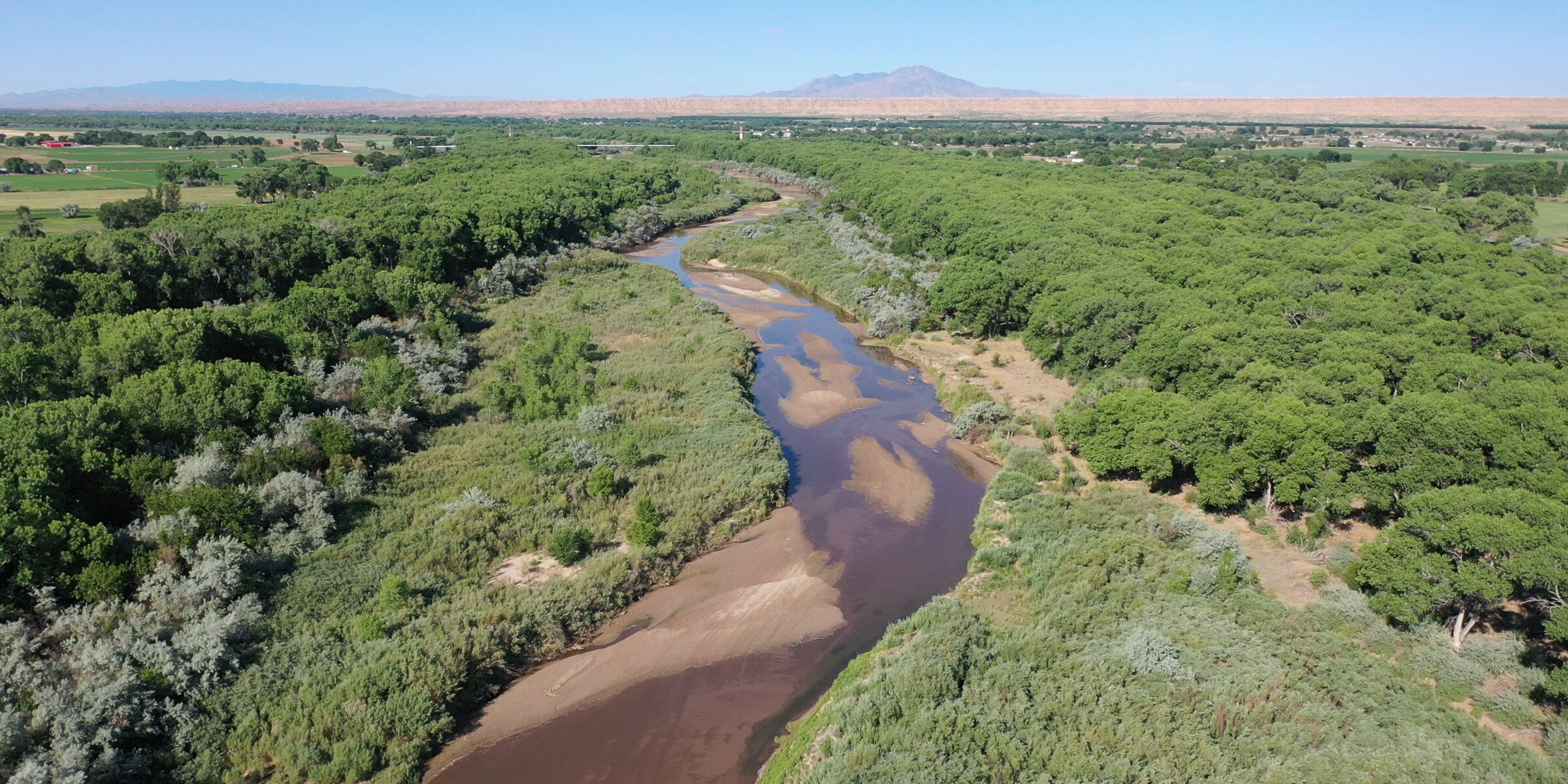 A stretch of the Rio Grande in New Mexico, a shallow but wide meandering river lined with lush vegetation.